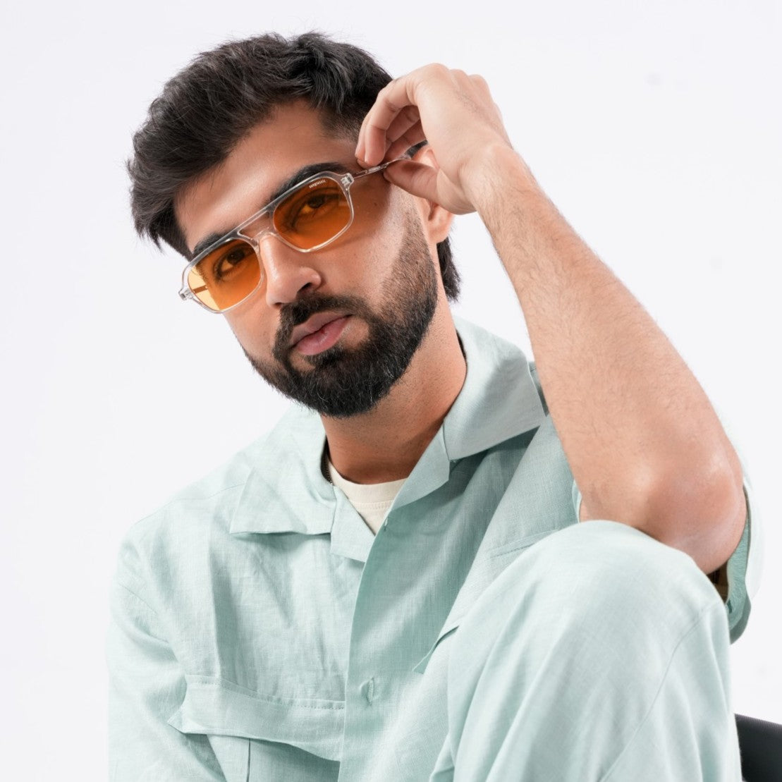 Male model wearing Milestone Green Square Sunglasses by Sunglassic. Featuring bold square frames in a muted green shade with tinted lenses, styled with a mint green shirt and neutral background.