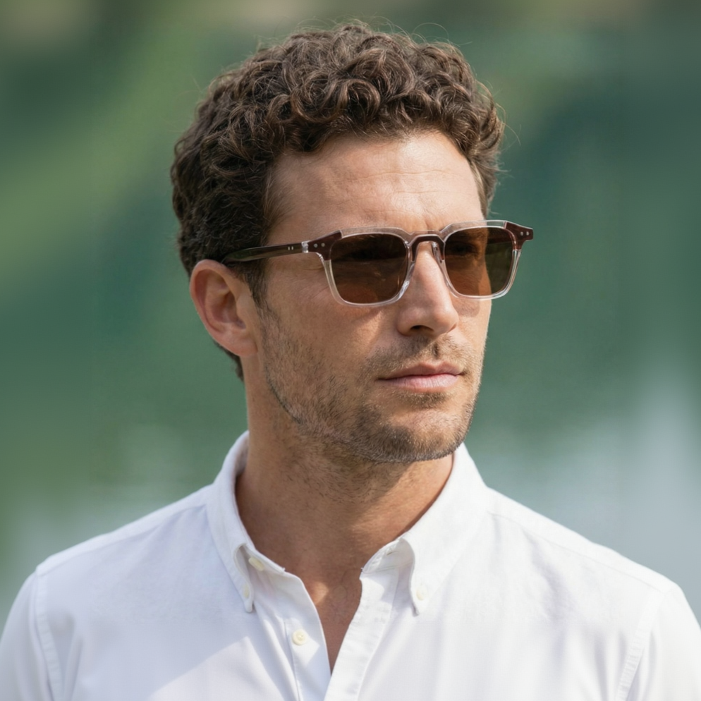 Man wearing sunglasses and a white shirt with a blurred green background