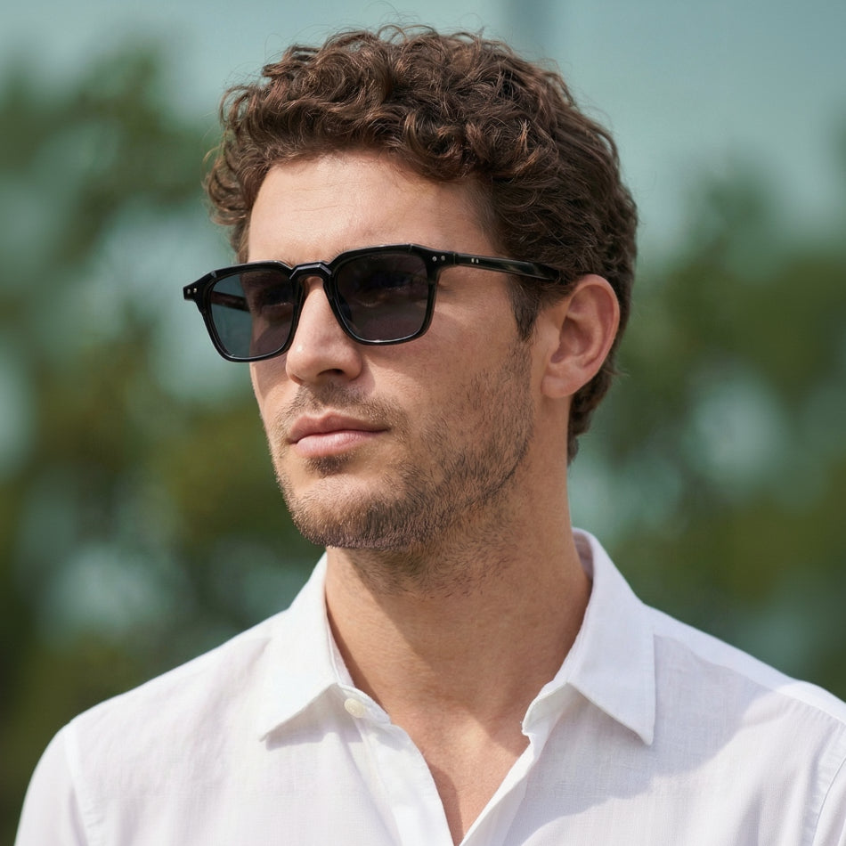 Man wearing sunglasses and a white shirt with a blurred natural background
