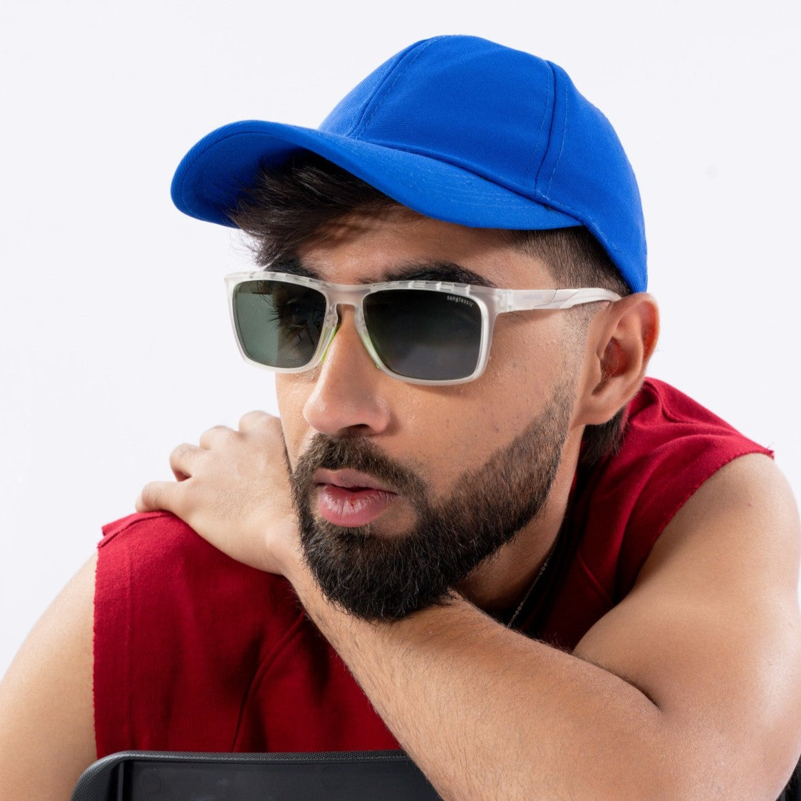 Hawk Clear Green Polarized Rectangle TR90 Sunglasses – Sunglassic.com. Male model wearing sporty clear-frame sunglasses with green-tinted polarized lenses, styled with a blue cap and red sleeveless top against a white background.