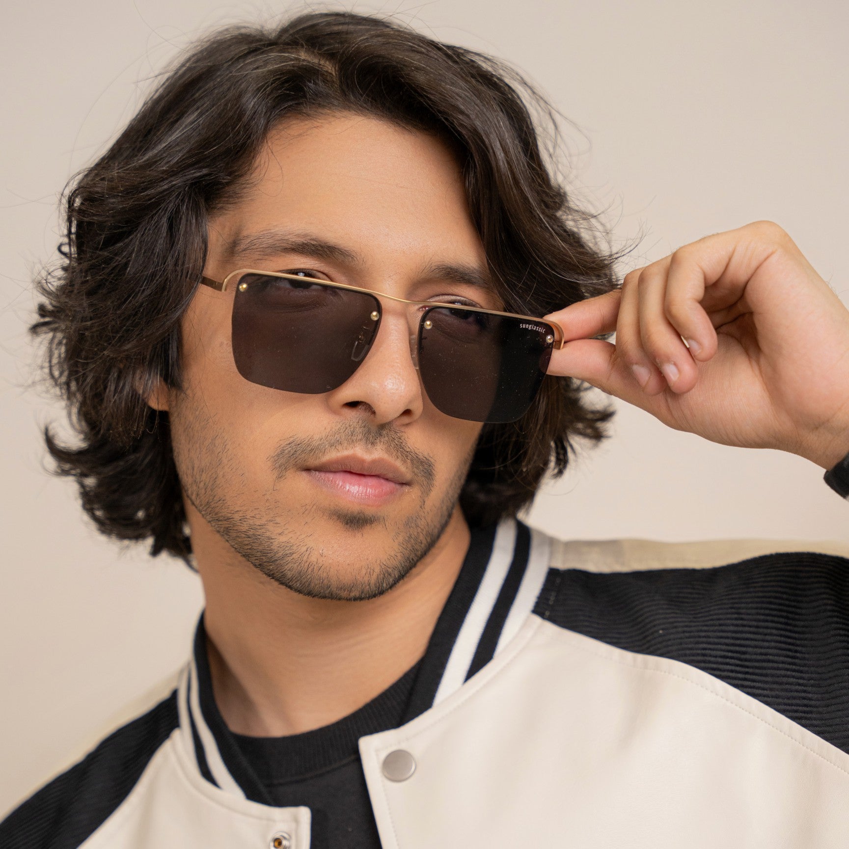 Heldish Gold Black Square Sunglasses – Sunglassic.com. Male model wearing square sunglasses with gold metal frames and black accents, styled in a pastel green shirt and beige tee, posing against a white background.