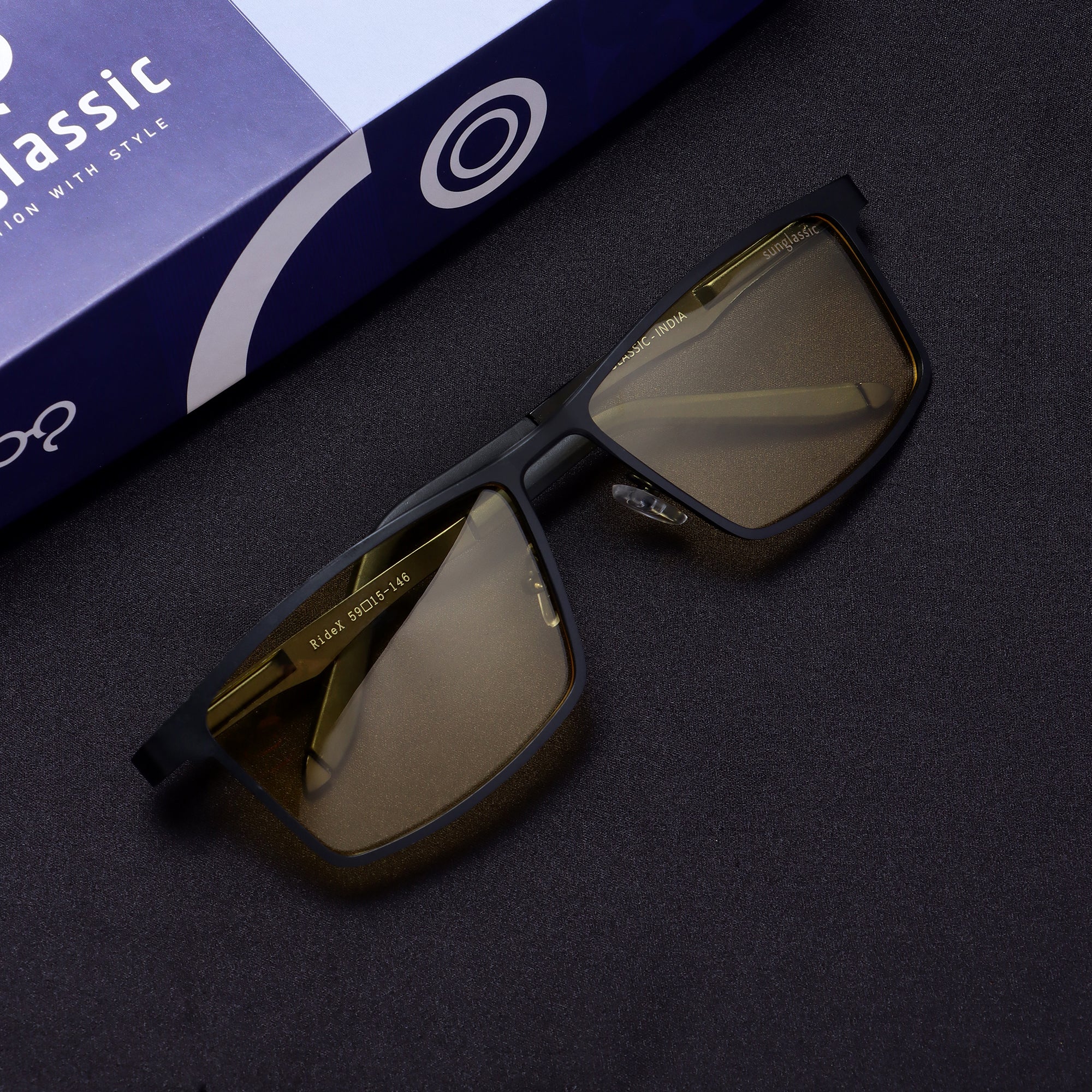 Top-down flat lay of RideX black yellow sunglasses with box