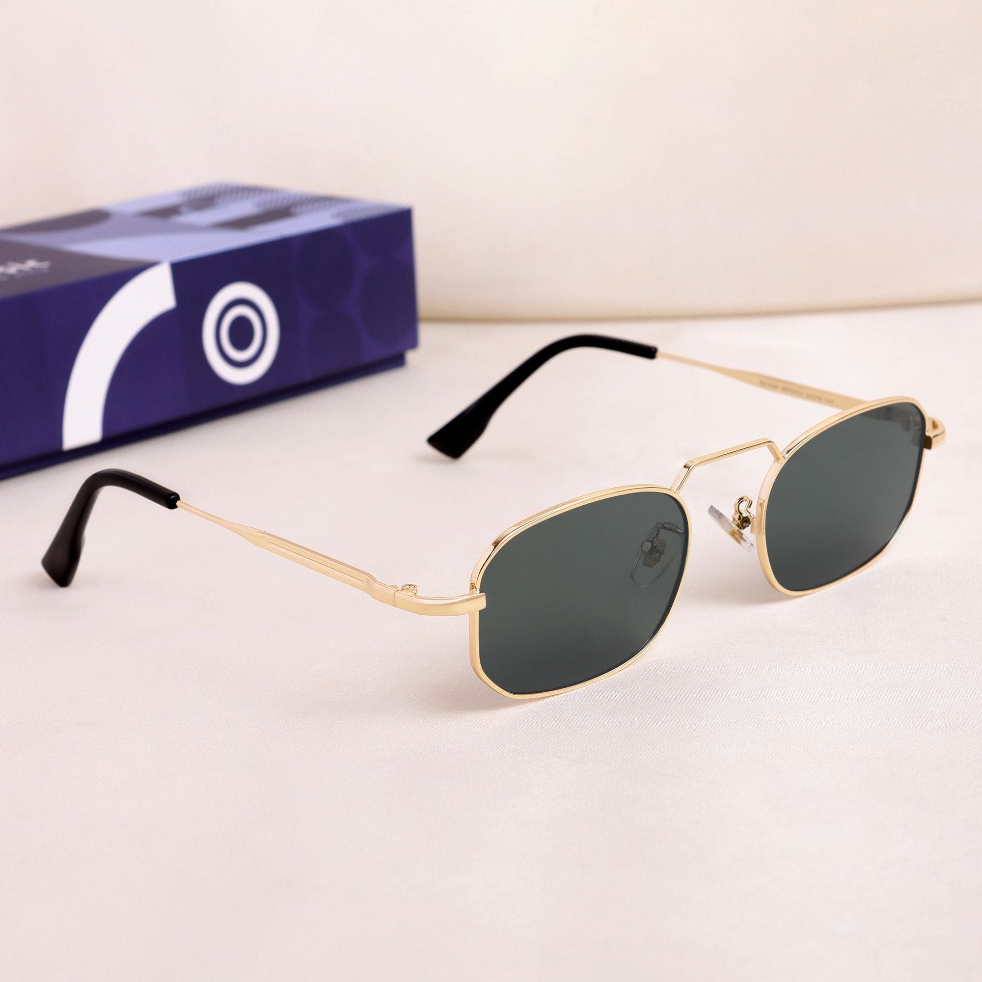 Gold-framed sunglasses with a box on a light background