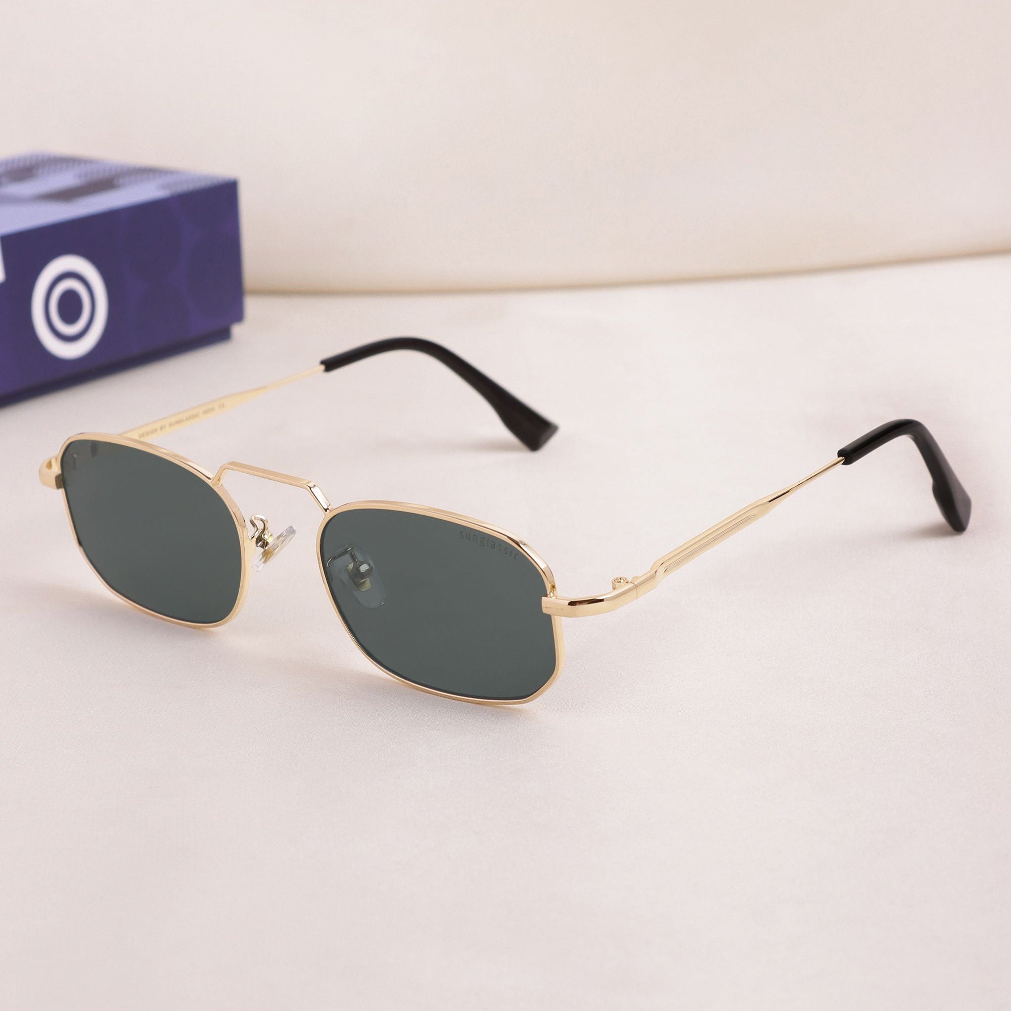 Gold-framed sunglasses with dark lenses on a light surface