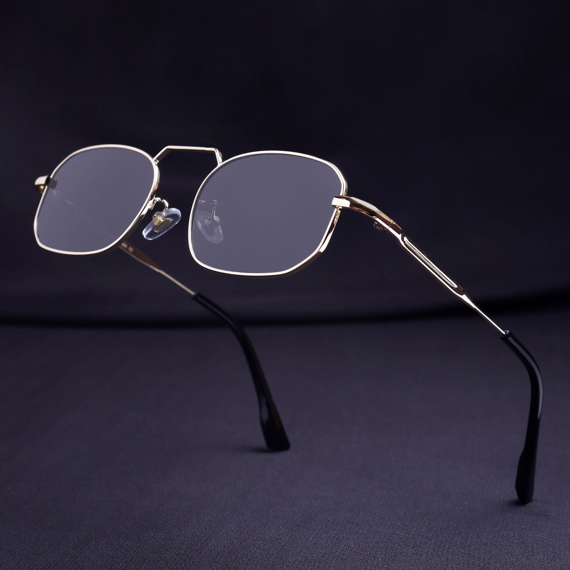 Eyeglasses with gold frame and dark lenses on a dark background