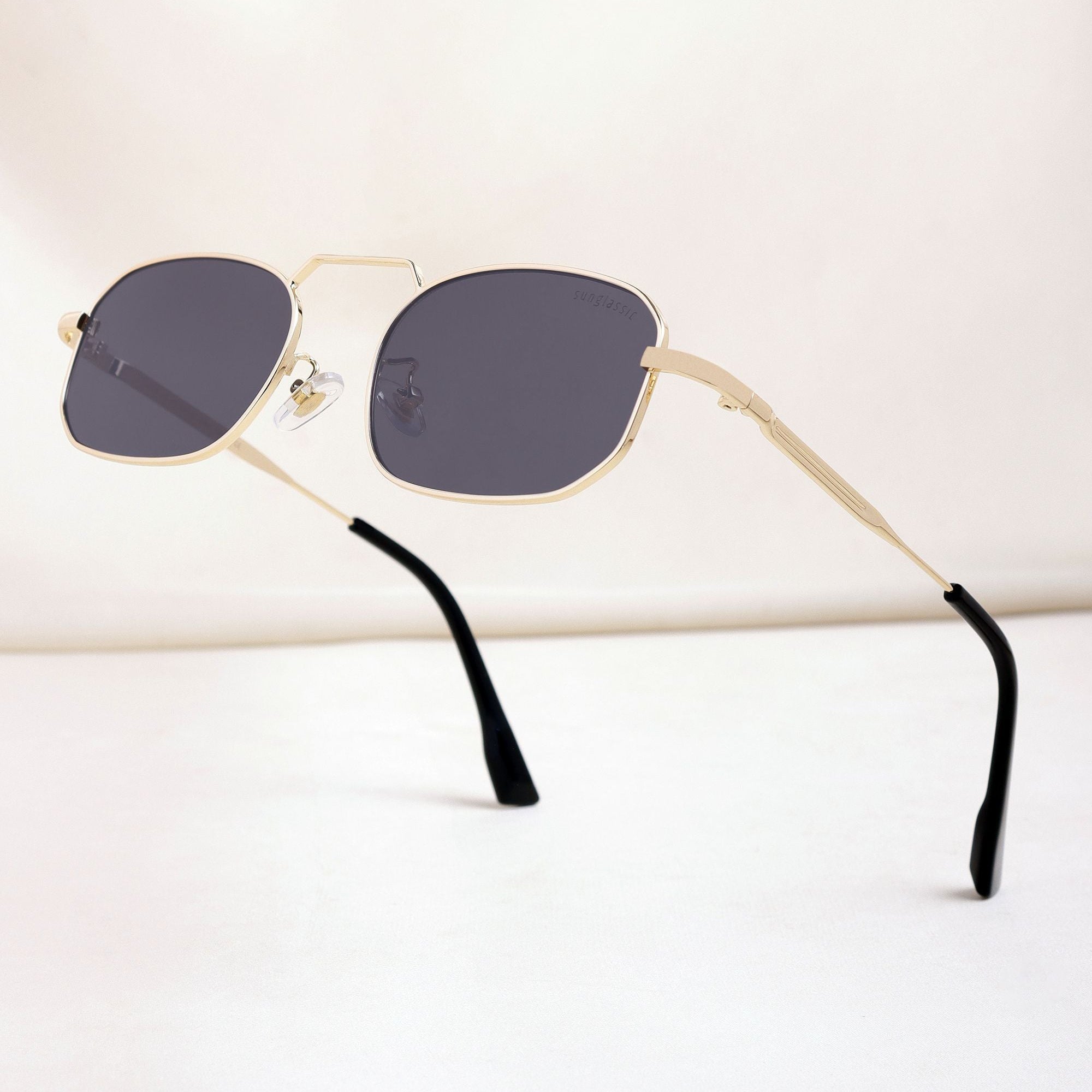 Sunglasses with gold frame and black lenses on a white background